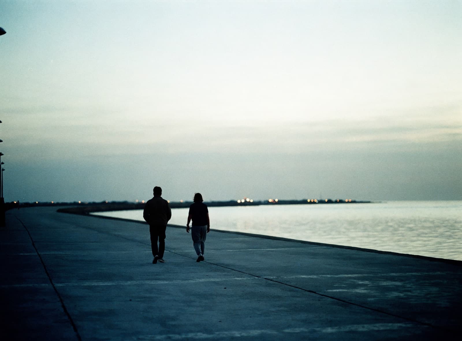 Two people walking along the waterfront at dawn